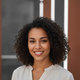 A candid, authentic portrait headshot of a smiling young woman, exuding confidence and satisfaction.